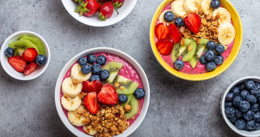 Açaí smoothie bowls topped with banana, strawberries, blueberries, kiwi, granola, and instant green kava.